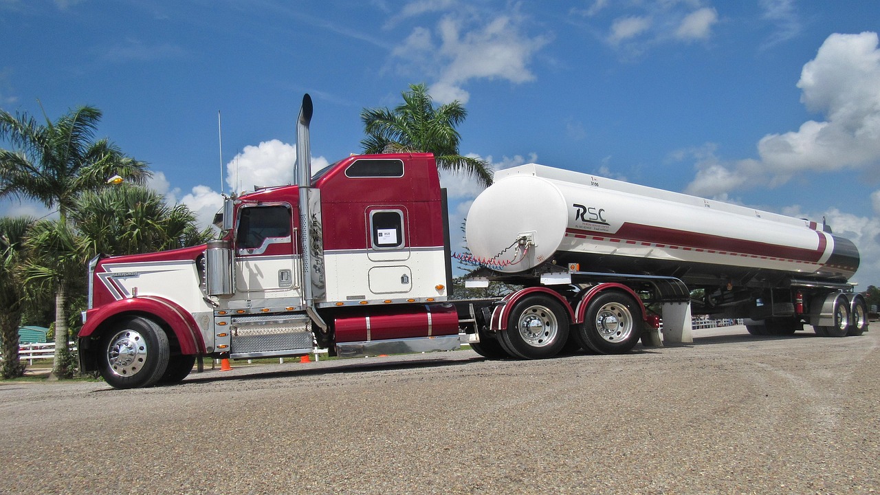 Грузовик Kenworth T370 на рабочей площадке, вид сбоку, с другими машинами на заднем плане, акцент на области двигателя.